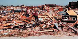 Grand Island residents in the South Loust area sort through piles of wreckage on June 4, 1980. Starr Elementary can be seen in the background. A few apartments (far right) survived the storm. 